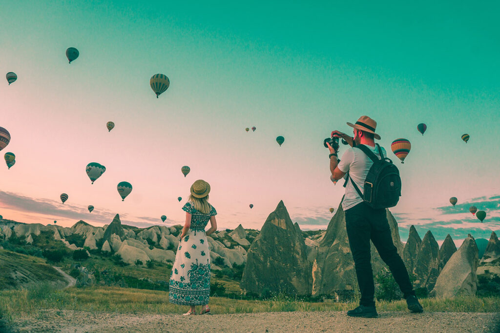 Man with a camera photographing woman and hot air balloons