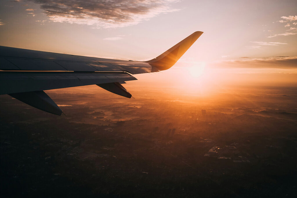 The wing of a flying jet at sunset