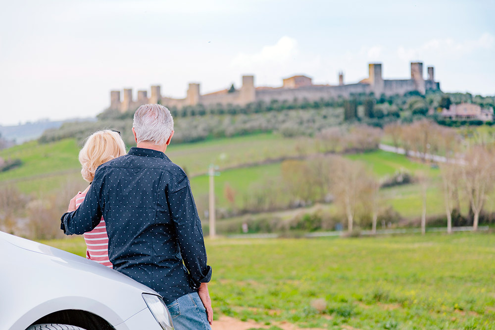 Rear view of tourist couple looking at fort in landscape, Siena, Tuscany, Italy